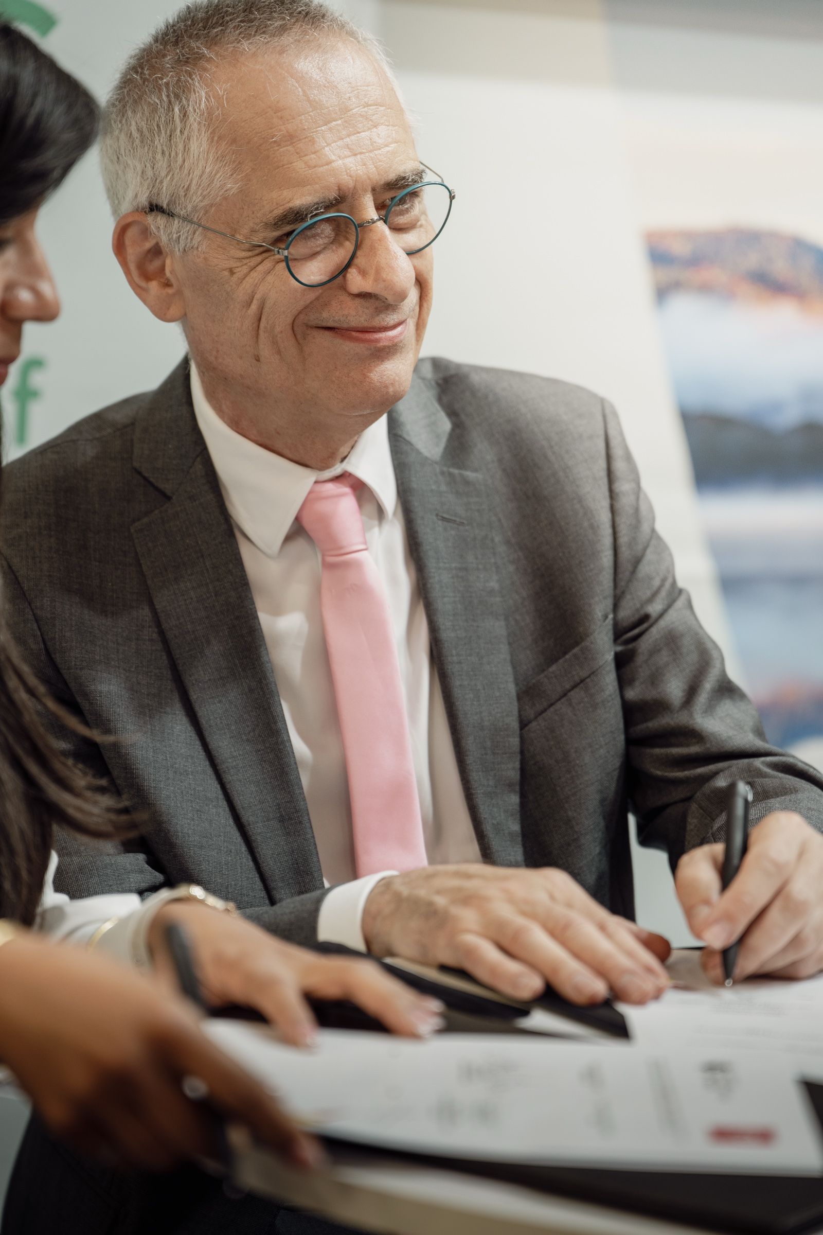 Un signataire paraphe l'accord, sourire aux lèvres