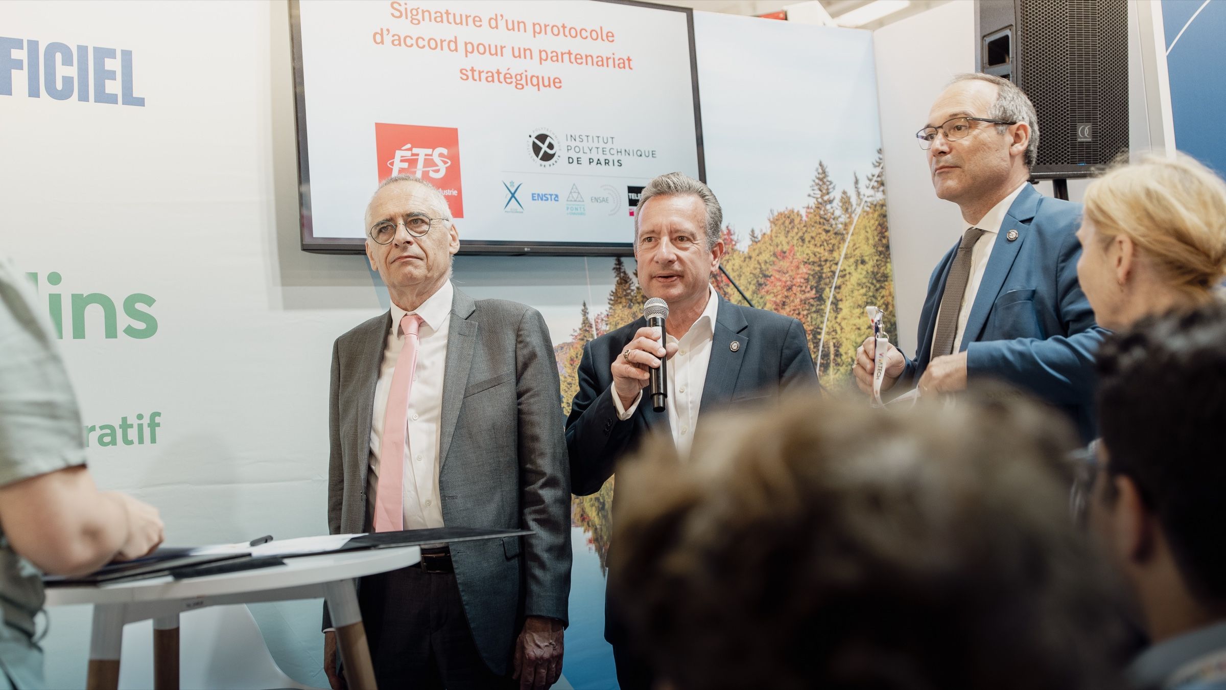 Intervenants au micro devant l'écran de l'ÉTS, au moment de la signature