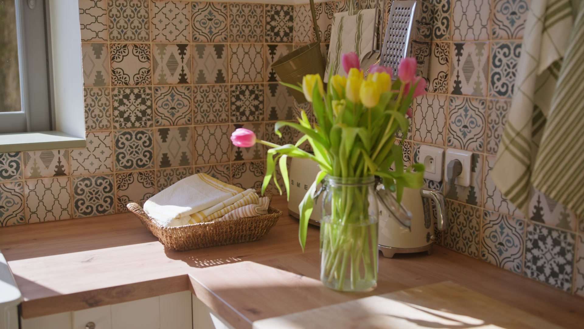 Cuisine baignée de soleil, bouquet de tulipes et linge de maison sur le plan de travail